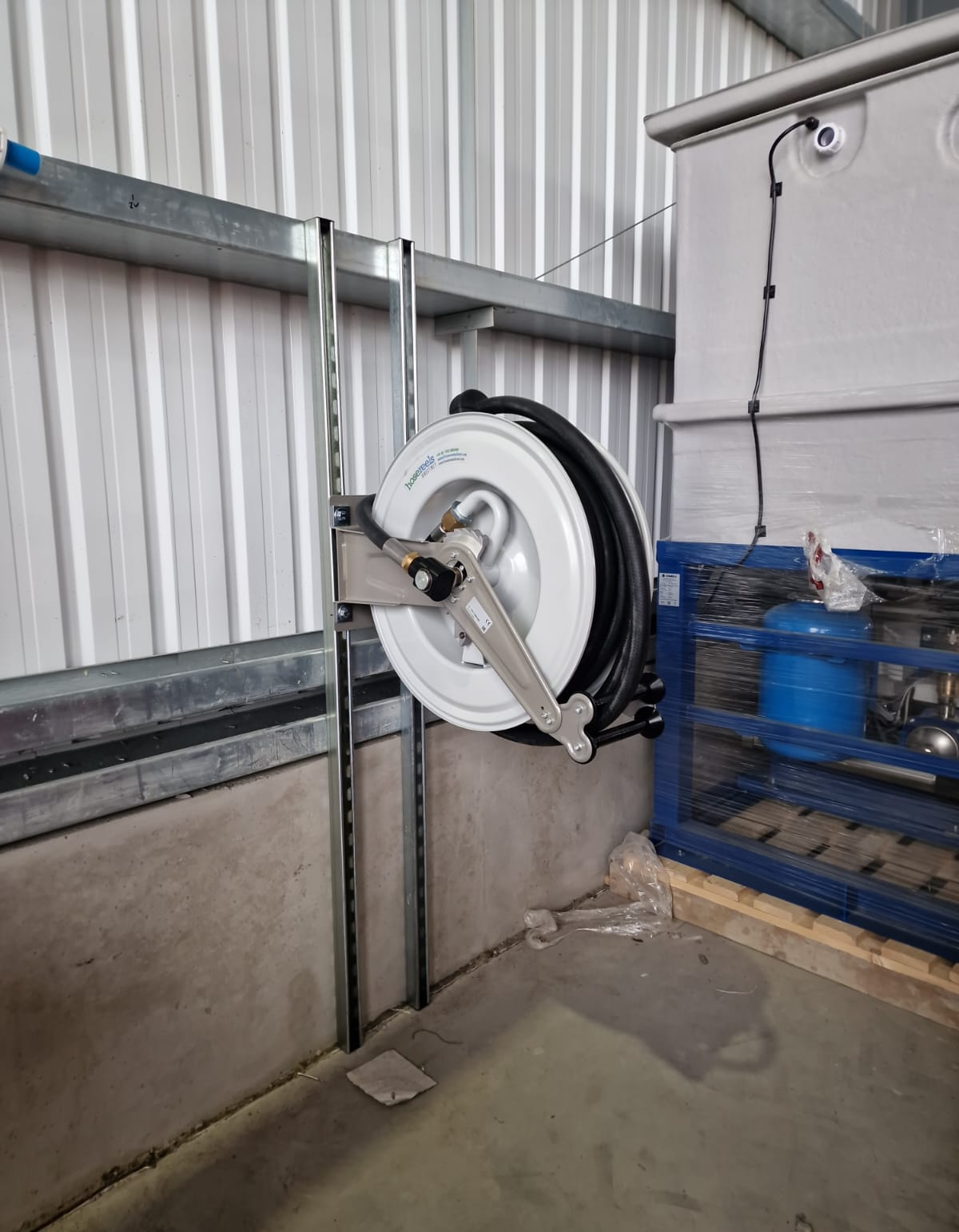 Wall-mounted hose reel beside the water storage and booster equipment