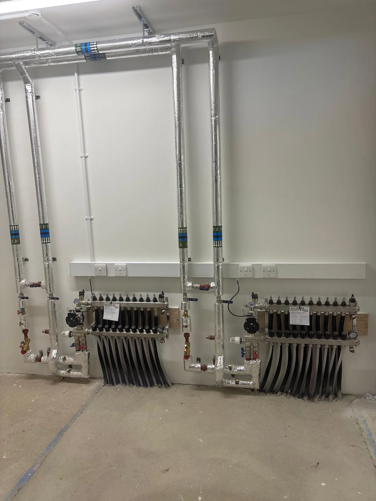 Two heating manifolds with circulation pumps and insulated connecting pipework
