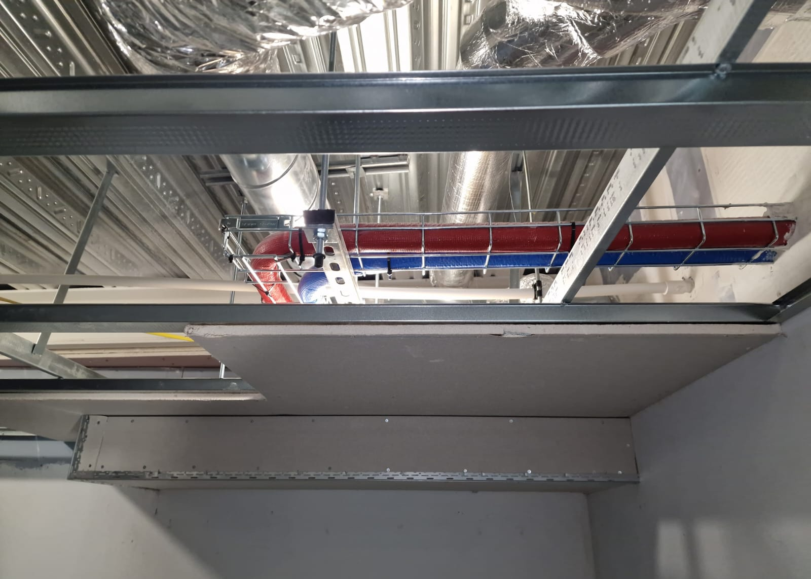 Red and blue insulated domestic water pipework above the ceiling