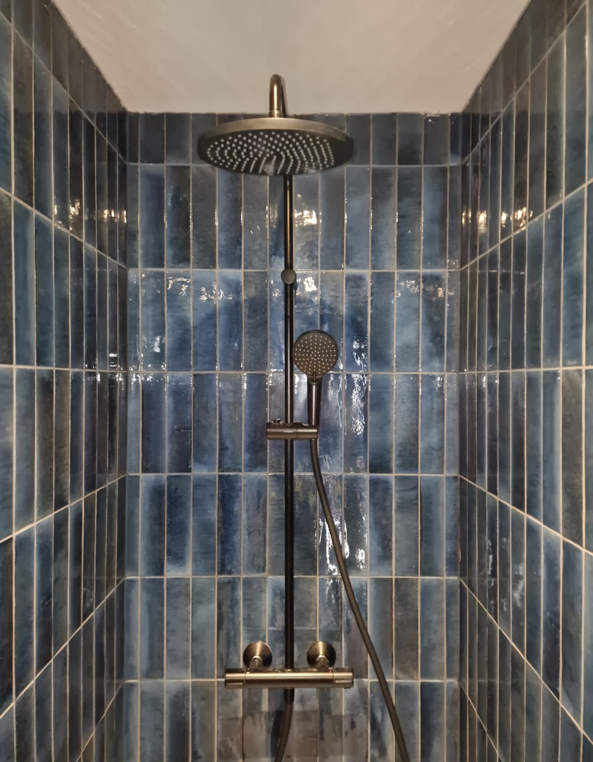 Installed shower head, controls and hand shower within a tiled enclosure