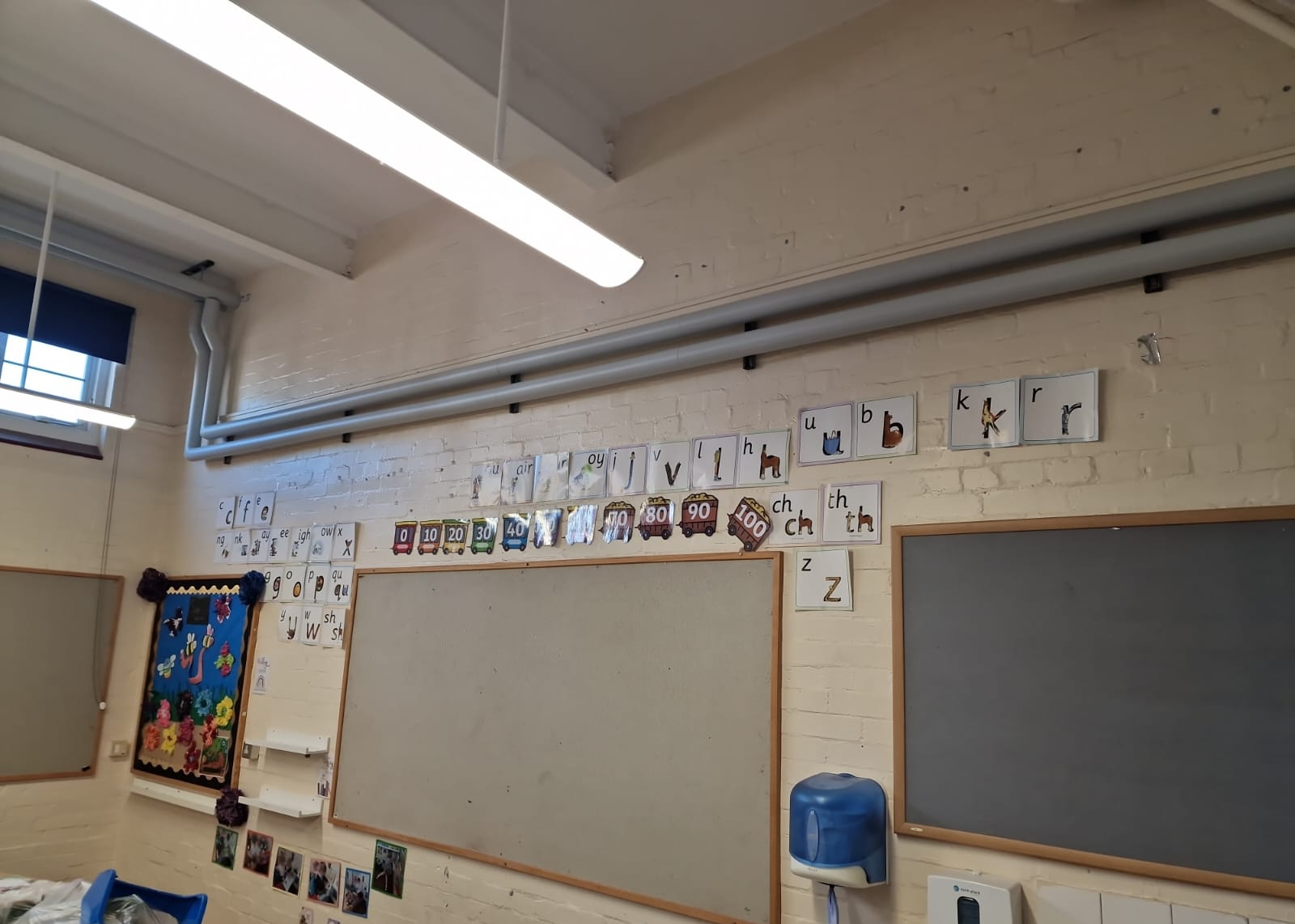 High-level insulated heating pipework above classroom display boards