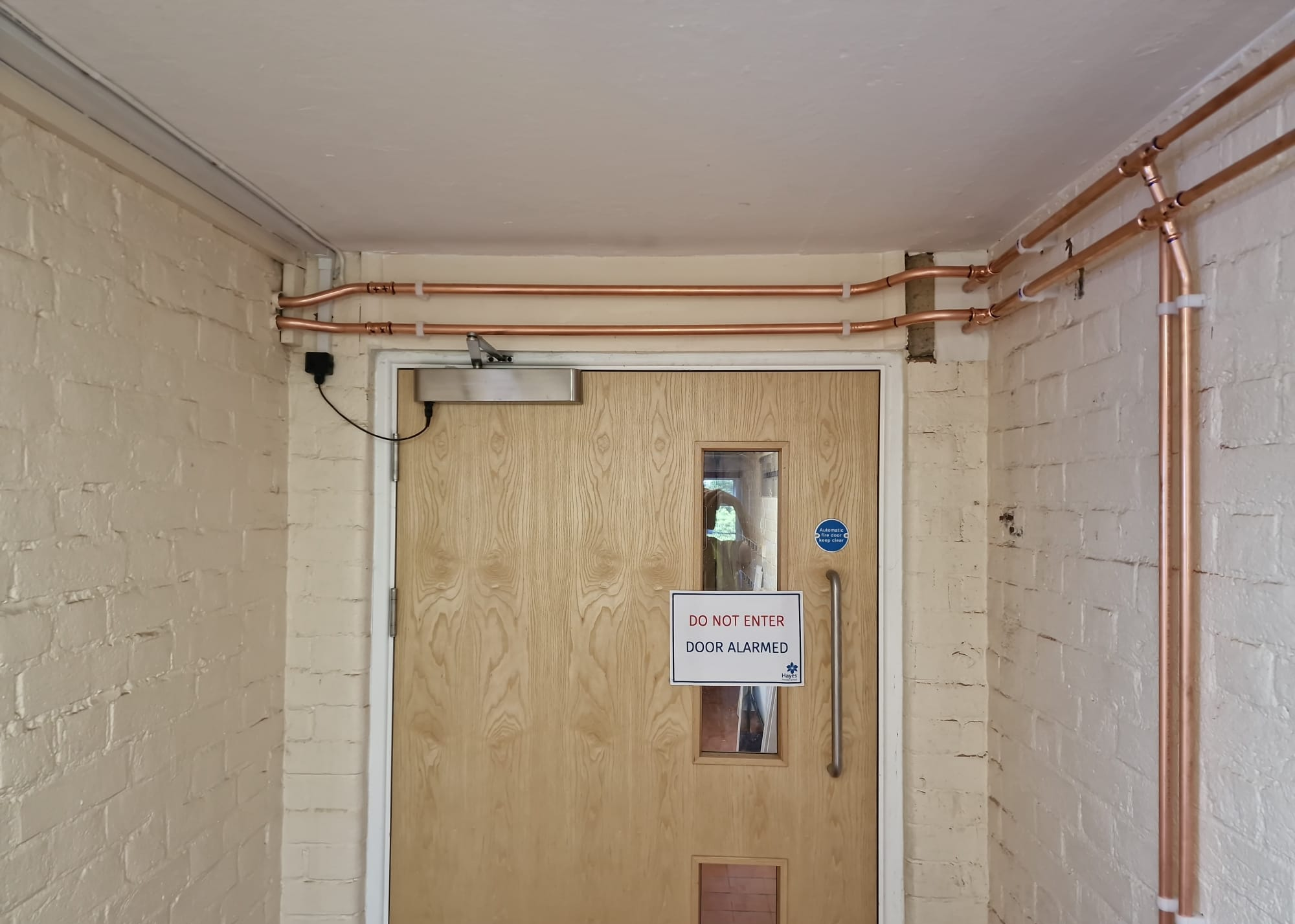 Copper heating pipework routed above a school doorway