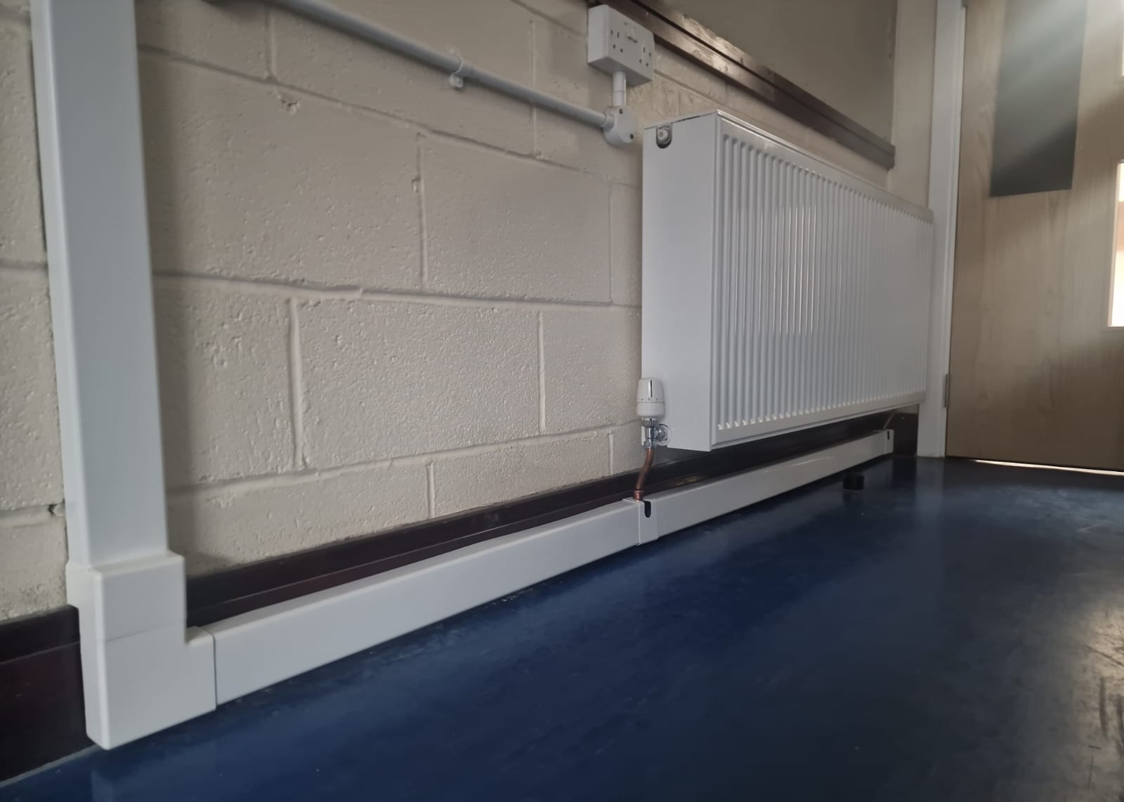 White panel radiator with valve and enclosed low-level pipework