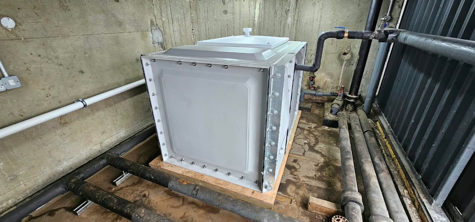 Sectional cold-water tank with insulated pipework and overflow connections in the existing enclosure
