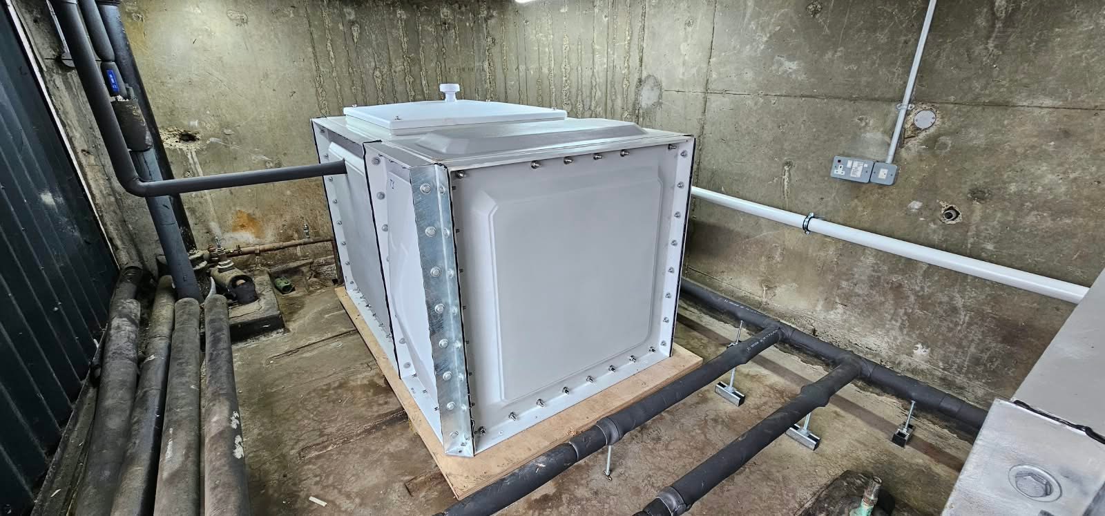Sectional cold-water tank and insulated pipework within the existing tank room