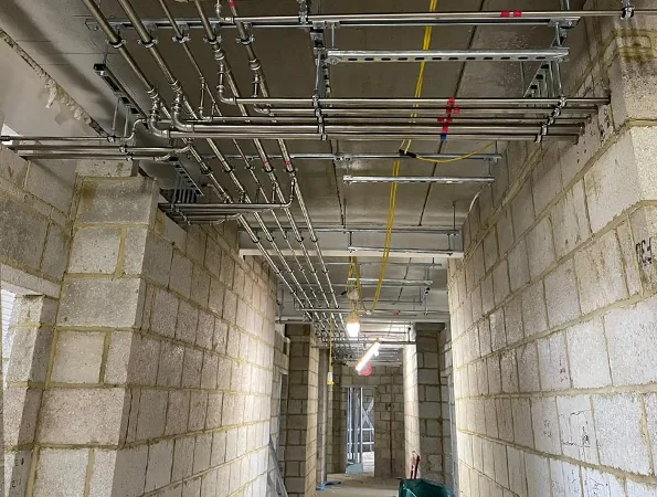 High-level pipework installation along a corridor during construction