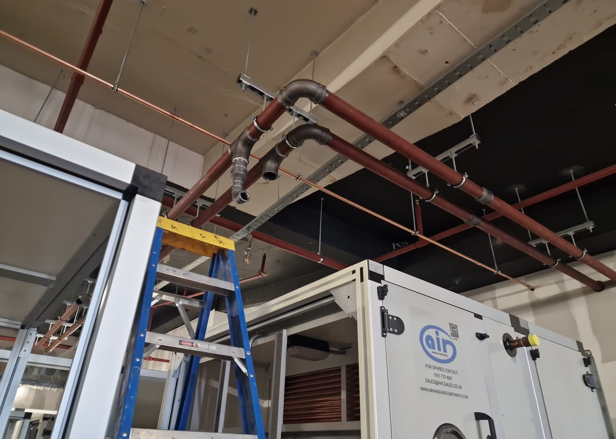 Overhead pipework above an air handling unit during installation