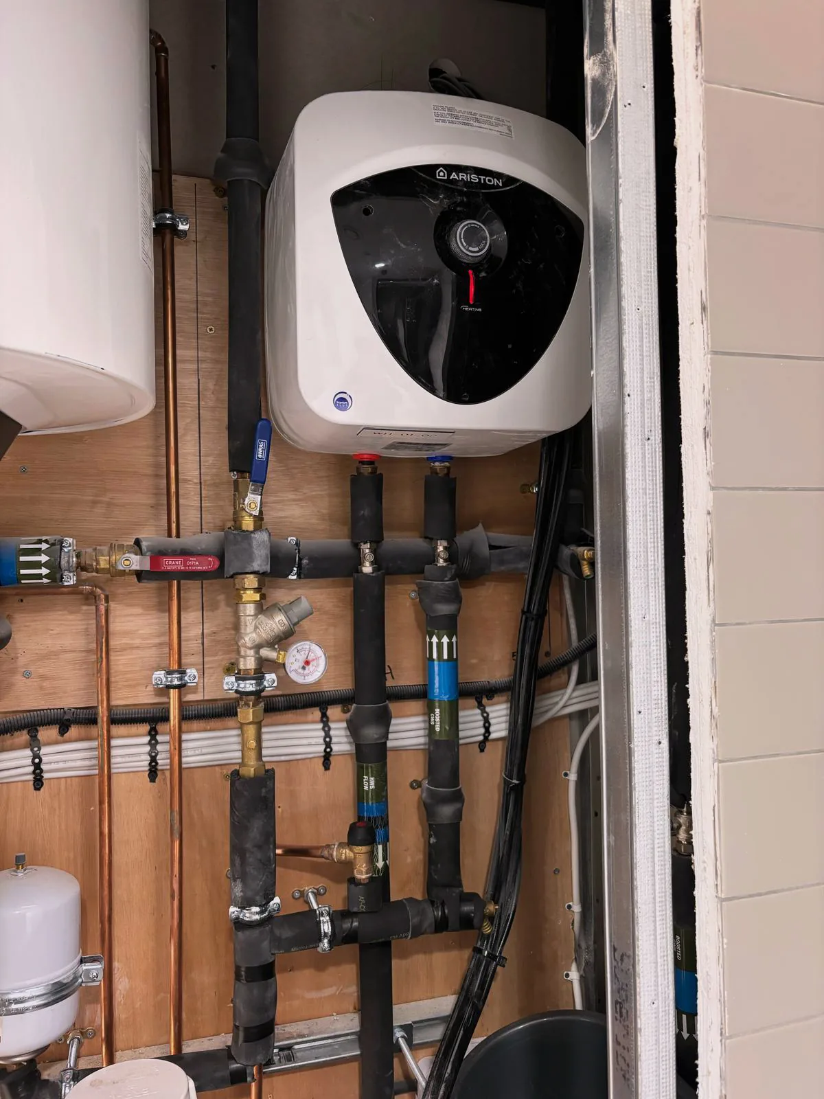 Water heater with insulated pipework, valves and pressure gauge