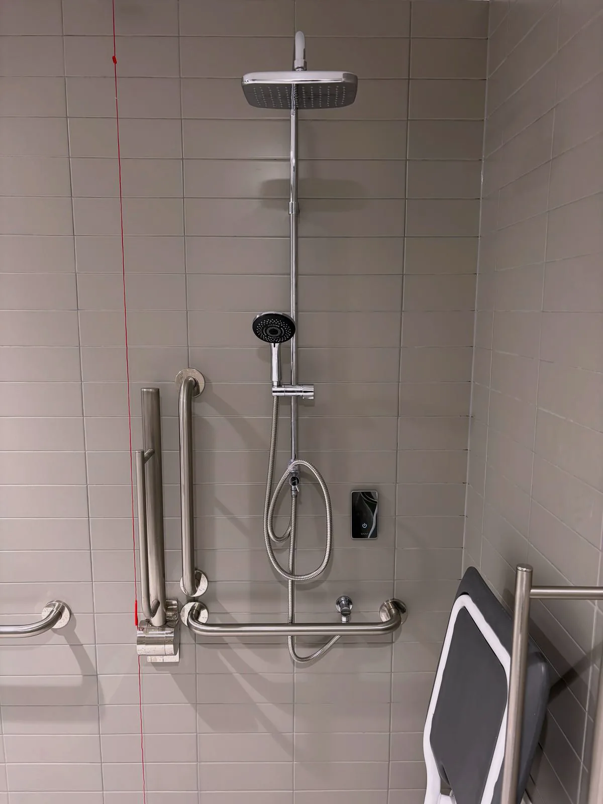 Accessible shower with overhead and hand showers, grab rails and folding seat